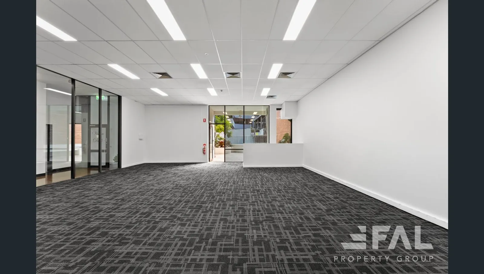 Carpeted open-plan ground-floor tenancy with reception counter and courtyard glazing