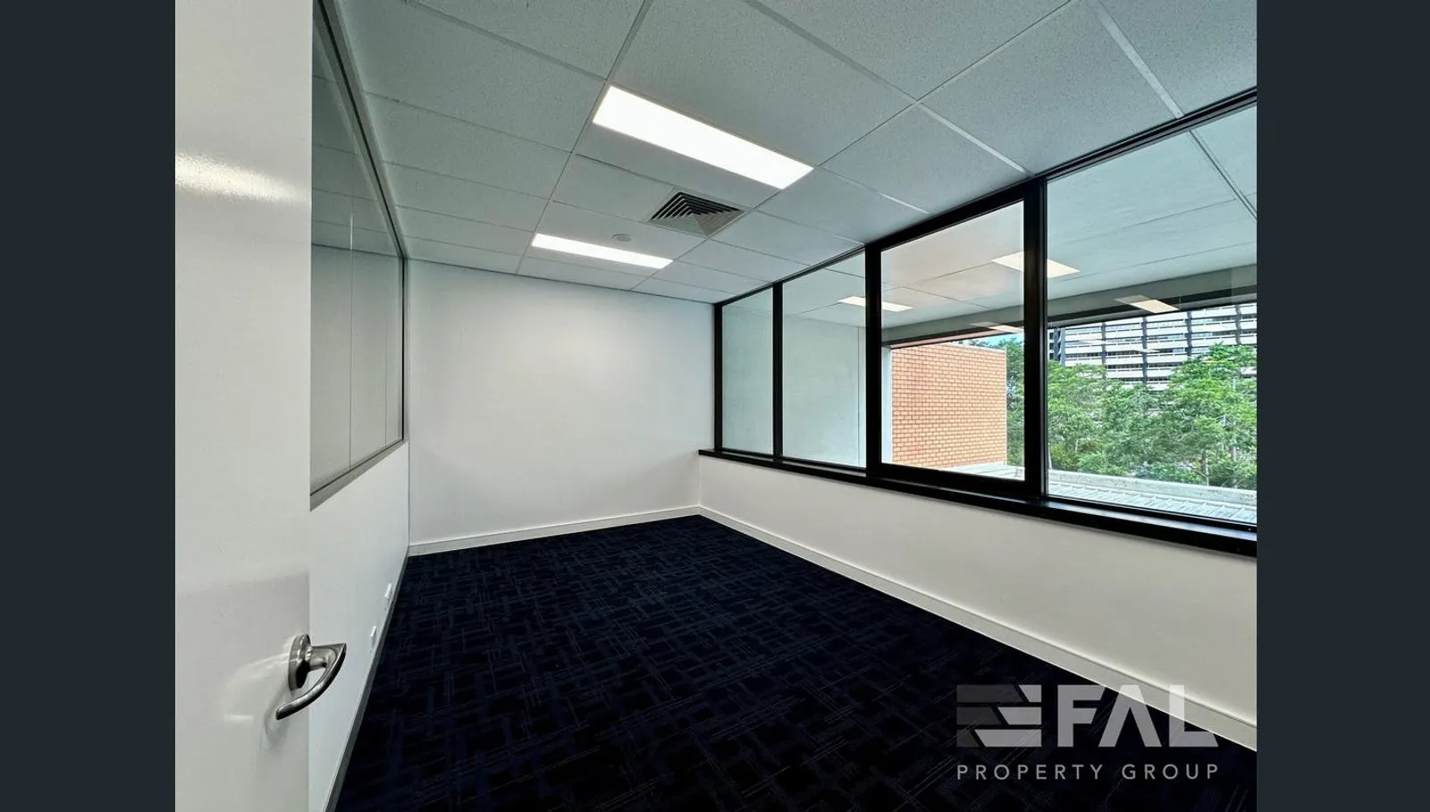 Carpeted private office with internal glazing and a leafy outlook